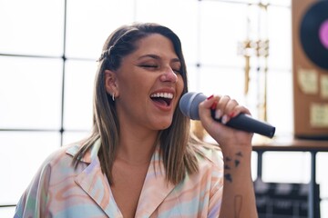 Fototapeta na wymiar Young hispanic woman artist singing song at music studio