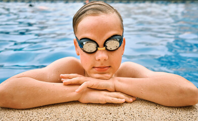 Smiling boy portrait in swimming goggles, Child swim in the pool, sunbathes, swimming in hot summer day. Relax, Travel, Holidays, Freedom concept.
