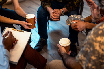 Close up of veterans hands holding cop of coffee during PTSD support group.