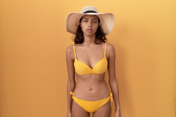 Young hispanic woman wearing bikini and summer hat looking sleepy and tired, exhausted for fatigue and hangover, lazy eyes in the morning.