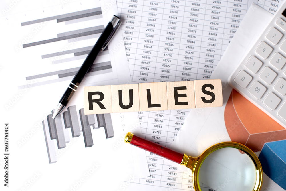 Poster RULES text on wooden block on graph background with pen and magnifier