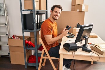 Young hispanic man ecommerce business worker using smartphone working at office