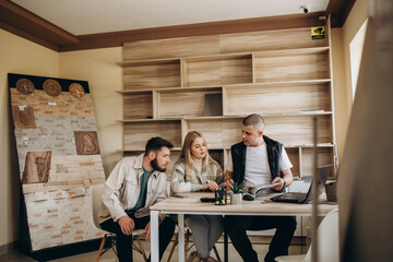 Fototapeta premium Competent seller consulting young couple about purchase of laminate flooring in store