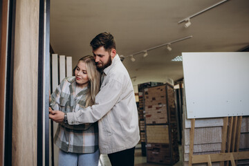 Fototapeta premium Beautiful young couple choosing ceramic tiles for their house repairment in the building shop.