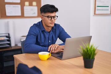 Young hispanic man business worker using laptop at office