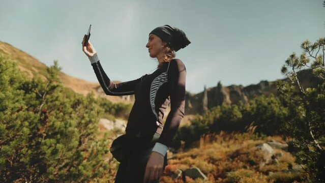 Tourist taking a photo with smartphone, sharing nature mountain landscape photo, enjoying vacation trip. The woman takes a selfie with her phone. Traveler spending vacation outdoors, trekking, hiking