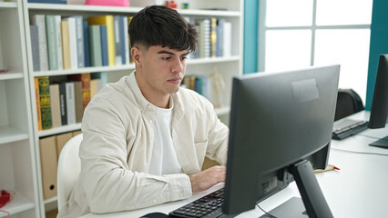 Fototapeta premium Young hispanic man student using computer studying at library university