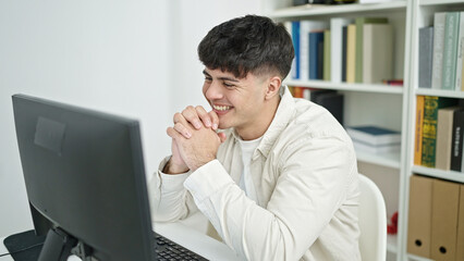 Young hispanic man student using computer studying at library university