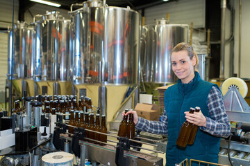 beautiful female brewery worker with bottling machinery