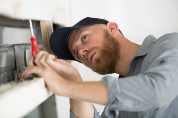 Naklejka na ściany i meble man drives screws into ceiling of fiberboard with a screwdriver