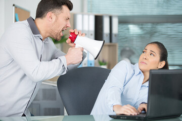 angry boss with megaphone screaming at employee in office