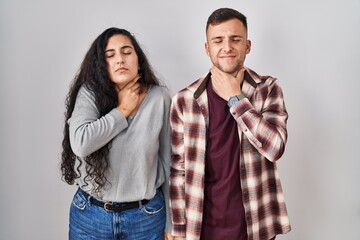 Young hispanic couple standing over white background touching painful neck, sore throat for flu, clod and infection