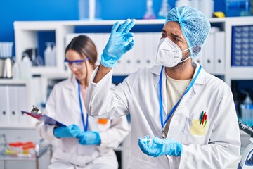 Fototapeta premium Man and woman scientists holding pills reading document at street