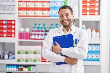 Young man pharmacist holding clipboard at pharmacy