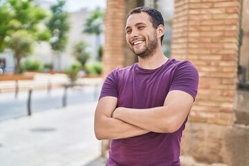 Fototapeta premium Young man smiling confident standing with arms crossed gesture at park