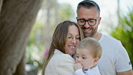 Family of mother, father and baby smiling together at park