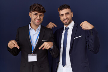 Two hispanic business men wearing business clothes looking confident with smile on face, pointing oneself with fingers proud and happy.