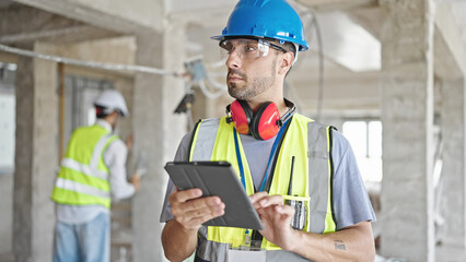 Two men builders using touchpad at construction site
