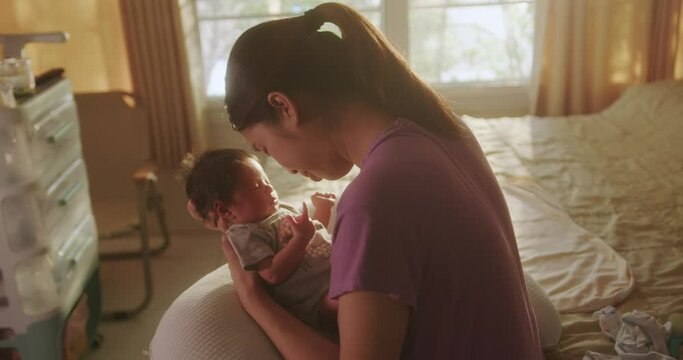 Asian mom is breastfeeding newborn at home