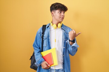 Hispanic teenager wearing student backpack and holding books smiling with happy face looking and...