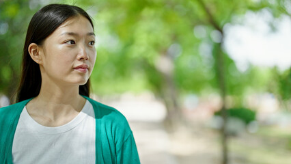 Young chinese woman looking to the side with serious expression at park