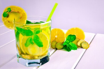 Drink in a glass on a white wooden table. Drink with lemon, ginger and mint.