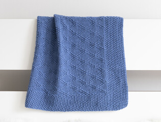 Navy blue knitted blanket in brocade knitting pattern on a white background