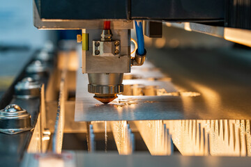 Robotic automatic laser cutting head with sparks cuts out the product along the contour of sheet metal on high-precision CNC machine
