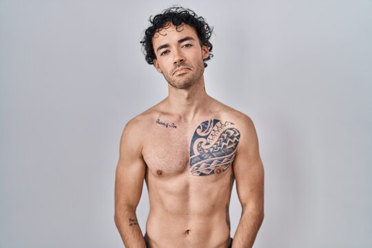 Hispanic man standing shirtless depressed and worry for distress, crying angry and afraid. sad expression.