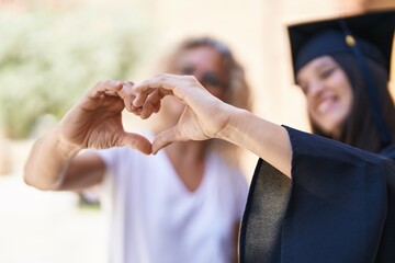 Two women mother and graduated daughter doing heart gesture with hands at campus university