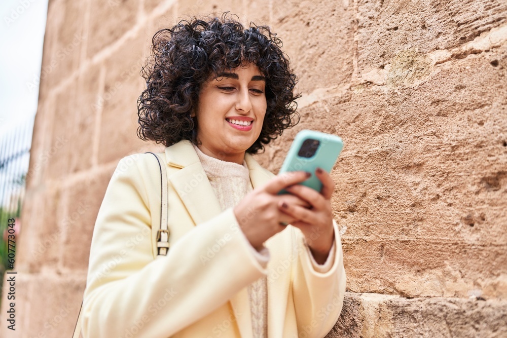 Poster young middle east woman excutive smiling confident using smartphone at street