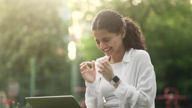 Young indian woman with crossed fingers wait for news celebrate online win success great news message feel happy on laptop and looking at camera with thumbs up at park Triumph Lucky Wow concept