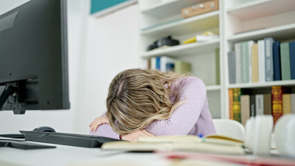 Young blonde woman student sleeping on table at classroom
