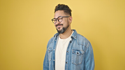 Obraz premium Young latin man smiling confident standing over isolated yellow background