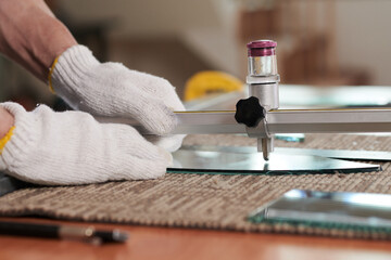 Crafts man measuring and cutting mirror piece