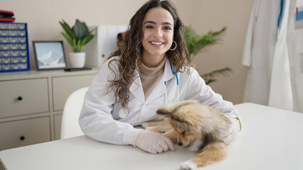 Young hispanic woman with dog veterinarian smiling confident at clinic