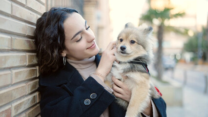 Young hispanic woman with dog smiling confident standing at street