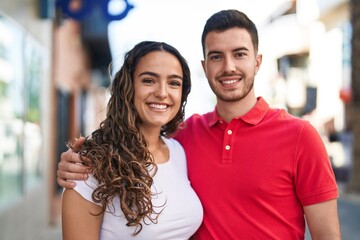Fototapeta premium Young hispanic couple smiling confident hugging each other at street