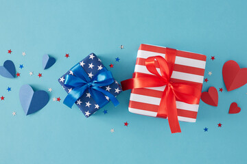 Fototapeta premium July 4th celebration theme concept. Top view flat lay of gift boxes with ribbon, blue and red hearts, star-shaped confetti on light blue background