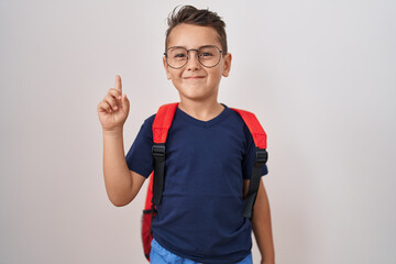 Little hispanic boy wearing glasses and student backpack smiling with an idea or question pointing finger with happy face, number one
