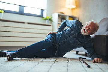 Senior man falling down on carpet and lying on the floor in living room at home, Falls of older...