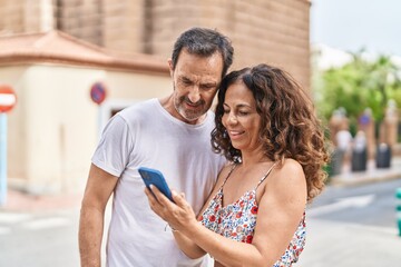 Obraz premium Man and woman couple smiling confident using smartphone at street