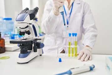 Fototapeta premium Young caucasian man scientist pouring liquid on test tube at laboratory