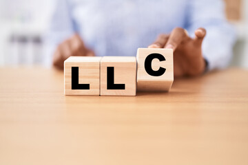 Black woman holding cubes with llc word on the table