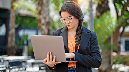 Young beautiful hispanic woman business worker using laptop with relaxed expression at coffee shop terrace