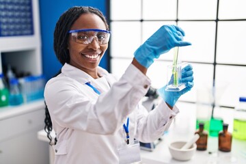 African american woman wearing scientist uniform measuring liquid laboratory