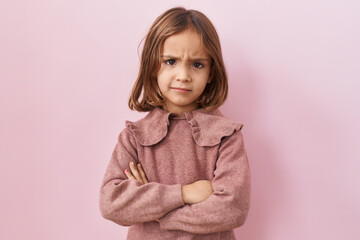 Little hispanic girl standing over pink background skeptic and nervous, disapproving expression on face with crossed arms. negative person.