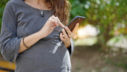 Young pregnant woman using smartphone at park