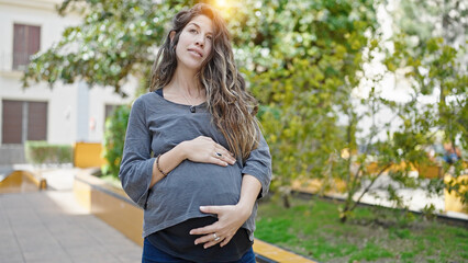 Obraz premium Young pregnant woman smiling confident touching belly at park