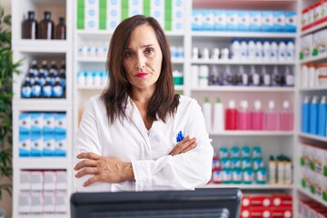 Middle age brunette woman working at pharmacy drugstore skeptic and nervous, disapproving...